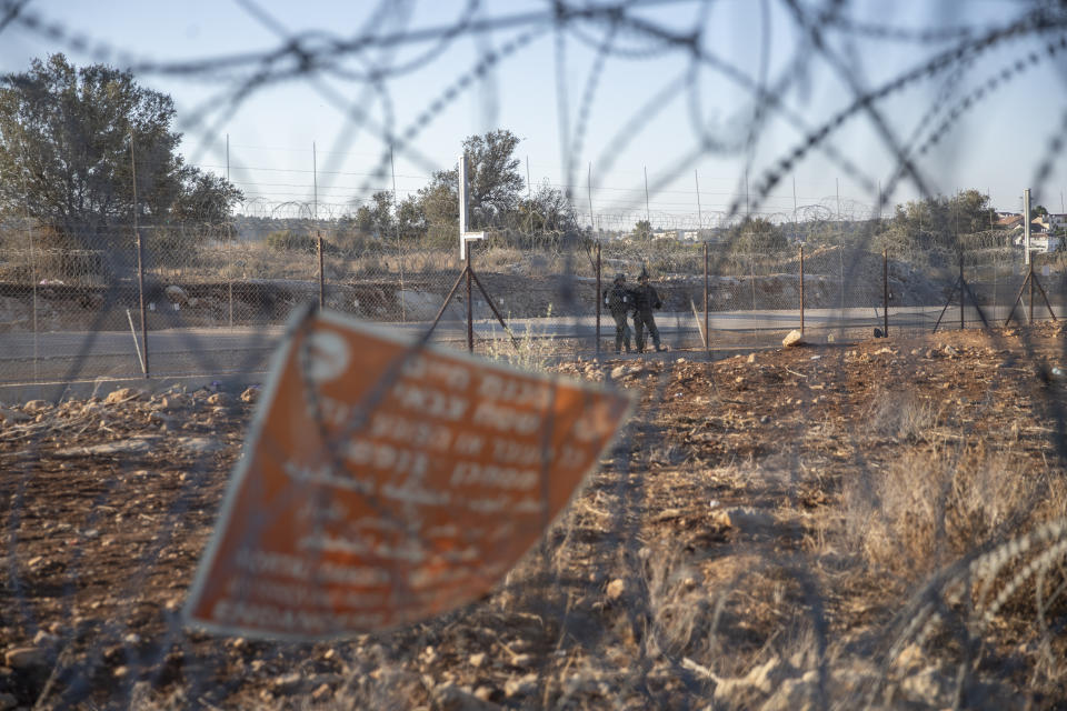 Israeli army soldiers guard a section of Israel's separation barrier, in the West Bank village of Nilin, west of Ramallah, Sunday, Nov. 7, 2021. Nearly two decades after Israel sparked controversy worldwide by building the barrier during a Palestinian uprising, it has become a seemingly permanent feature of the landscape — even as Israel encourages its citizens to settle on both sides. (AP Photo/Nasser Nasser)