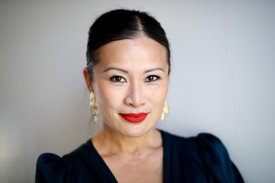 Poh Ling Yeow wears a navy dress, gold earrings and red lipstick at the L'Oréal Paris Revitalift Retinol Launch on May 26, 2021 in Sydney, Australia