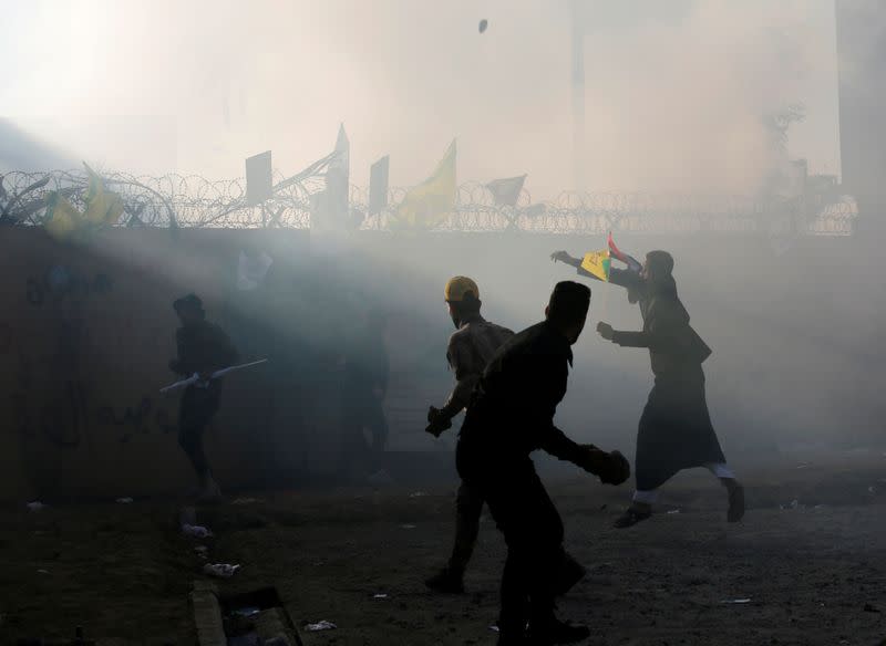 FILE PHOTO: Protesters and militia fighters throw stones towards the U.S. Embassy during a protest to condemn air strikes on bases belonging to Hashd al-Shaabi (paramilitary forces), in Baghdad