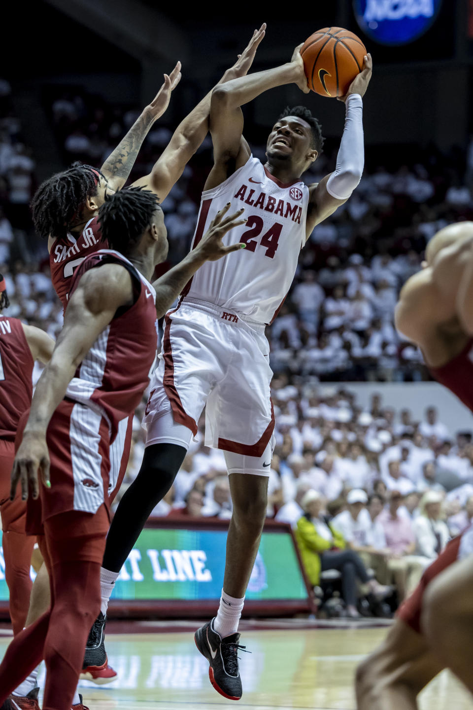 Alabama forward Brandon Miller (24) fires off a shot with Arkansas guard Nick Smith Jr. (3) and guard Davonte Davis (4) defending during the second half of an NCAA college basketball game, Saturday, Feb. 25, 2023, in Tuscaloosa, Ala. (AP Photo/Vasha Hunt)