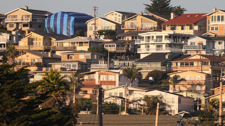 Houses in Morro Bay face the sunset above the Morro Bay High School football stadium, with one tented for fumigation, on Friday, Aug., 25, 2023.