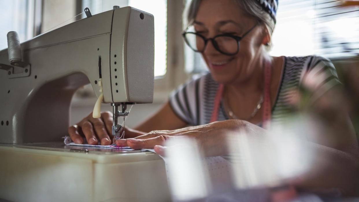 Senior woman working at the sewing machine at home.