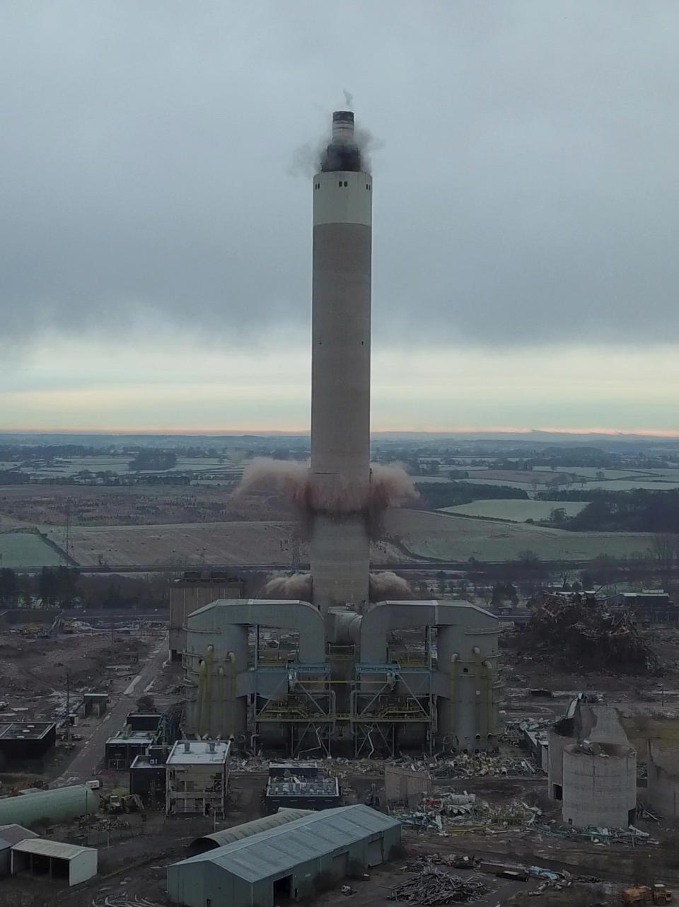 Dozens of spectators gathered to watch the dramatic moment a 183-metre (600ft) tall iconic power station chimney was demolished in a controlled explosion. The imposing concrete tower at Rugeley Power Station collapsed in just four seconds in a cloud of dust. Between 50 and 100 residents gathered on a nearby hillside to watch the spectacle unfold despite police warning people to avoid travelling to the area during lockdown. The massive chimney was demolished using explosive charges to pave the way for new development in the area - including hundreds of homes, a school and offices.