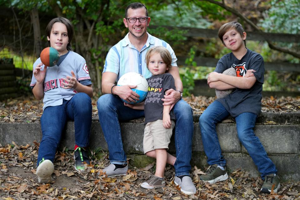 Brandon Long, of Fort Thomas, sits with his boys, Eliah, 11, Gideon, 3, and Micaiah, 9, after throwing a football and kicking the soccer ball around in their backyard on Oct. 25. The family has decided not to pursue playing organized contact football after the sudden cardiac arrest of Damar Hamlin earlier this year.