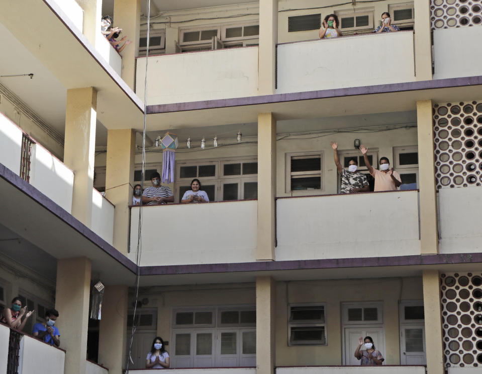 Neighbors applaud as a photojournalist returns home following his quarantine after he tested positive for COVID 19, in Mumbai, India, Sunday, April 26, 2020. (AP Photo/Rajanish Kakade)