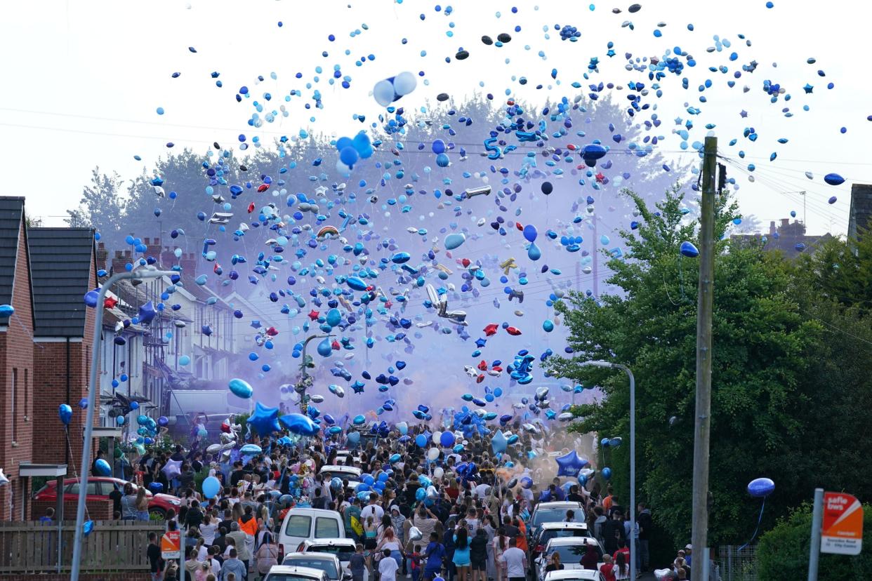 People release balloons during a vigil for the victims of a road traffic collision on Snowden Road in Ely, Cardiff (PA)