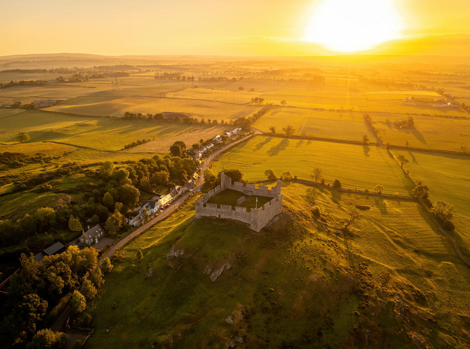 Sunset behind Hume Castle from a drone very yellow-orange view