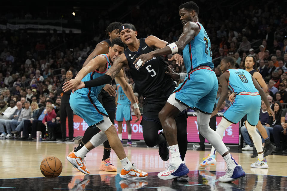 Orlando Magic forward Paolo Banchero loses the ball trying to drive between Phoenix Suns guard Devin Booker and center Deandre Ayton (22) during the first half of an NBA basketball game, Thursday, March 16, 2023, in Phoenix. (AP Photo/Rick Scuteri)
