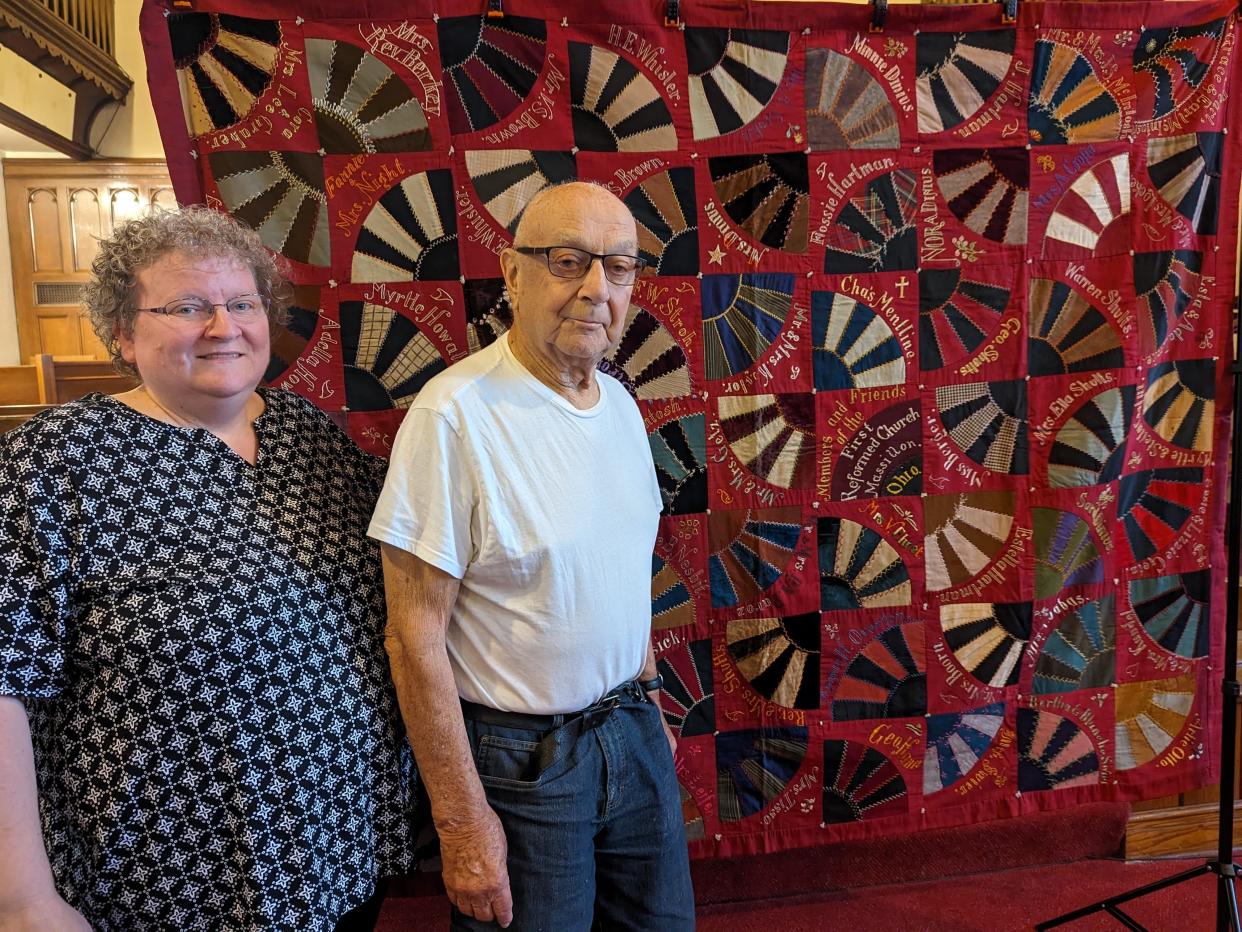 The Rev. Karen McEwen, senior pastor at Grace United Church of Christ in Massillon, and longtime member Stan Crofut stand in front of a historic quilt made by congregants in the 1920s and thought to be long gone until it was discovered this year in Texas.