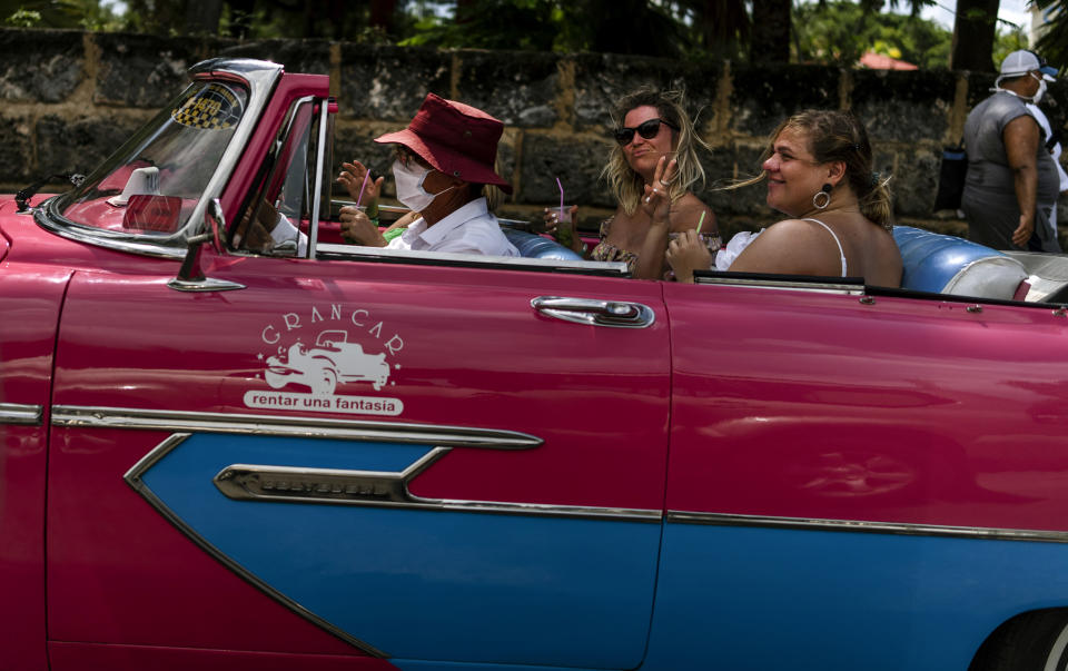 Tourists enjoy a mojito while traveling in a vintage American car during a city tour of Varadero, Cuba, Wednesday, Sept. 29, 2021. Authorities in Cuba have begun to relax COVID restrictions in several cities like Havana and Varadero. (AP Photo/Ramon Espinosa)