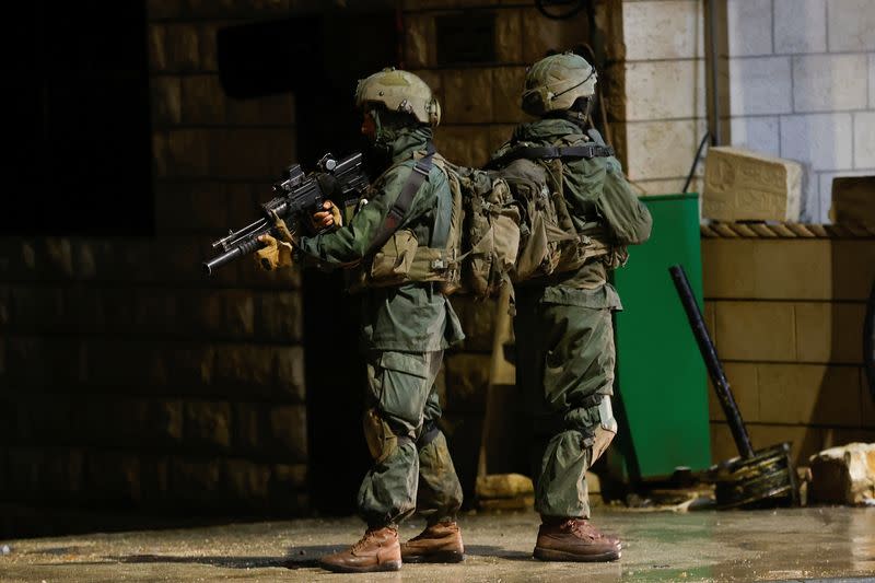 Israeli troops stand guard at the scene of a shooting, in Huwara