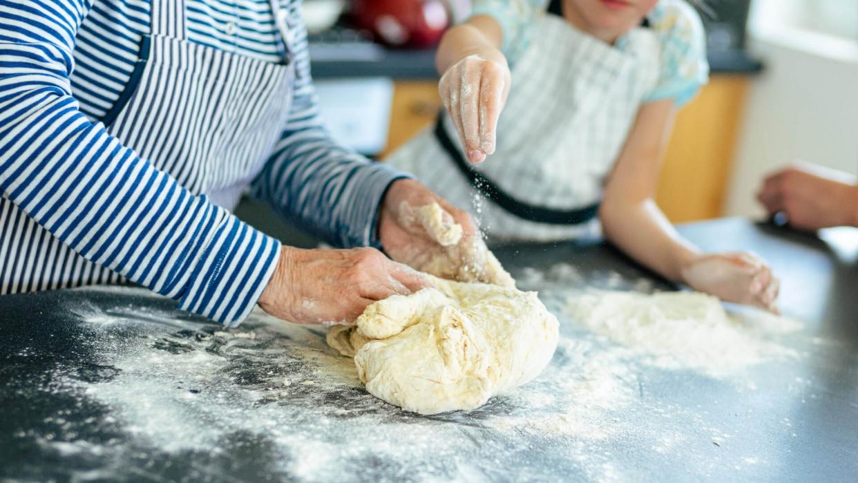 Close-up of a grandmother, mother and daughter making a dough.