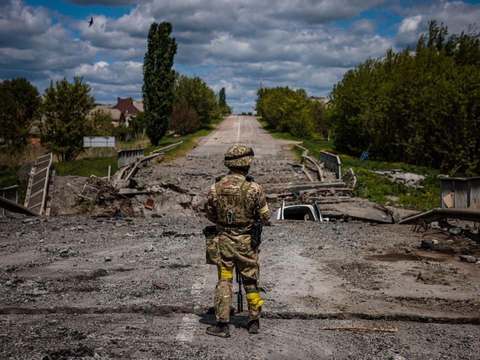 A soldier of the Kraken Ukrainian special forces unit observes a destroyed bridge on the road near the village of Rus'ka Lozova, north of Kharkiv, on 16 May  (AFP/Getty)