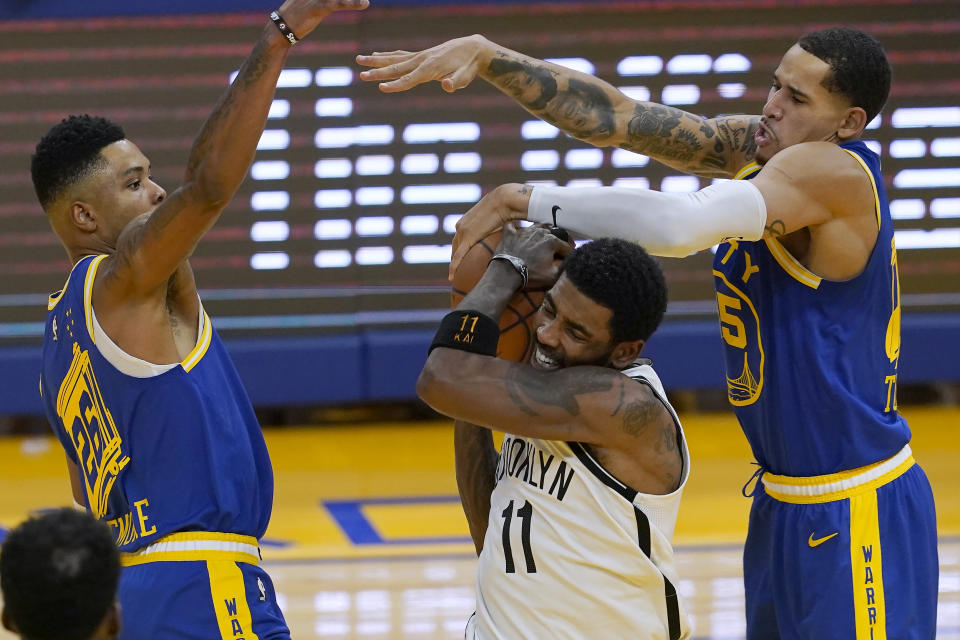 Brooklyn Nets guard Kyrie Irving (11) is defended by Golden State Warriors forwards Kent Bazemore, left, and Juan Toscano-Anderson during the first half of an NBA basketball game in San Francisco, Saturday, Feb. 13, 2021. (AP Photo/Jeff Chiu)