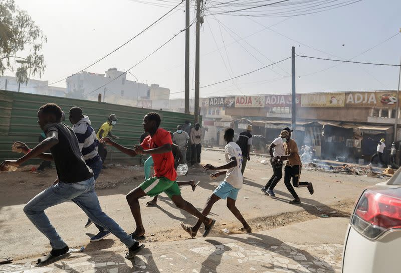 Senegalese demonstrators run away during clashes with riot police as they protest against the postponement of the Feb. 25 presidential election, in Dakar