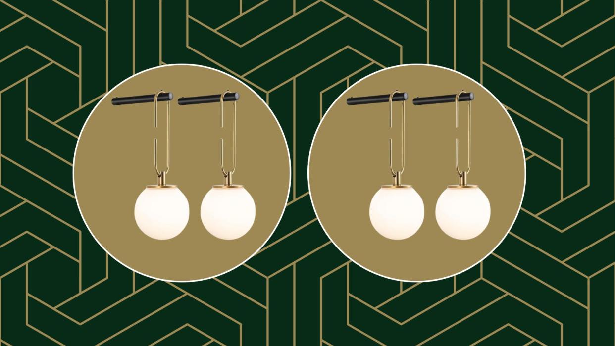  The Amazon wall sconces hanging from a black hook on a green and gold geometric background. 