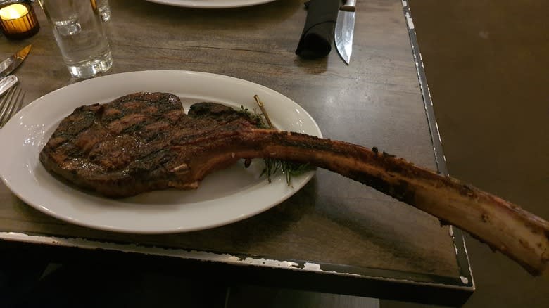 large bone-in tomahawk steak on white plate