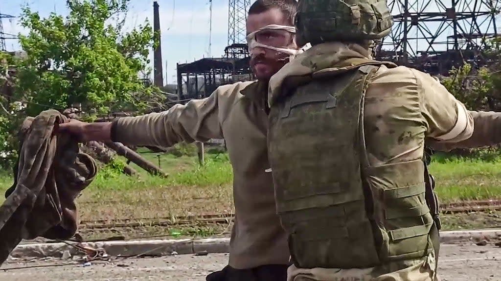 A Ukrainian serviceman is searched by a pro-Russian military official after leaving the besieged Azovstal steel plant in Ukraine’s port city of Mariupol (Russian Defence Ministry/AFP via)