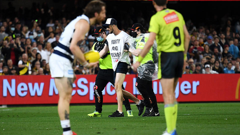 A pitch invader is escorted from the field by security during the 2020 AFL Grand Final between Richmond and Geelong. (Photo by Quinn Rooney/Getty Images)