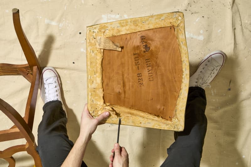 overhead shot of the staples being taken out of the original chair cushion.