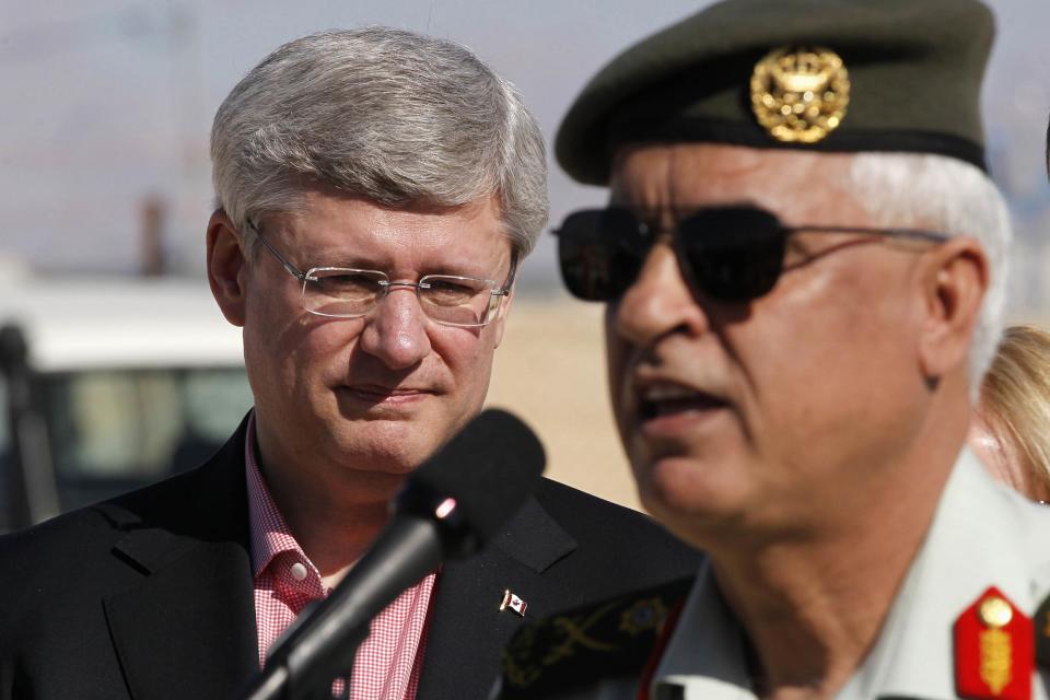 Prime Minister Stephen Harper (L) listens to Major General Omar al-Khalidi, head of the Planning Commission of the Jordanian army, during a tour at the main center of the World Food Program during their visit to Al Zaatrai refugee camp, in the Jordanian city of Mafraq, near the border with Syria January 24, 2014. REUTERS/Muhammad Hamed