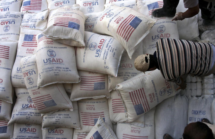 FILE - In this June 4, 2008 file photo, Palestinians unload bags of flour donated by the United States Agency for International Development, USAID, at a depot in the West Bank village of Anin near Jenin. Tens of thousands of Palestinians are no longer getting food aid or health services from America after the Trump administration’s decision in 2018 to cut more than $200 million in aid to the Palestinians. Before the aid cuts were announced, it provided food aid -- branded as a gift from the American people -- to more than 180,000 Palestinians in the Israeli-occupied West Bank and Gaza on behalf of the World Food Program. (AP Photo/Mohammed Ballas, File)