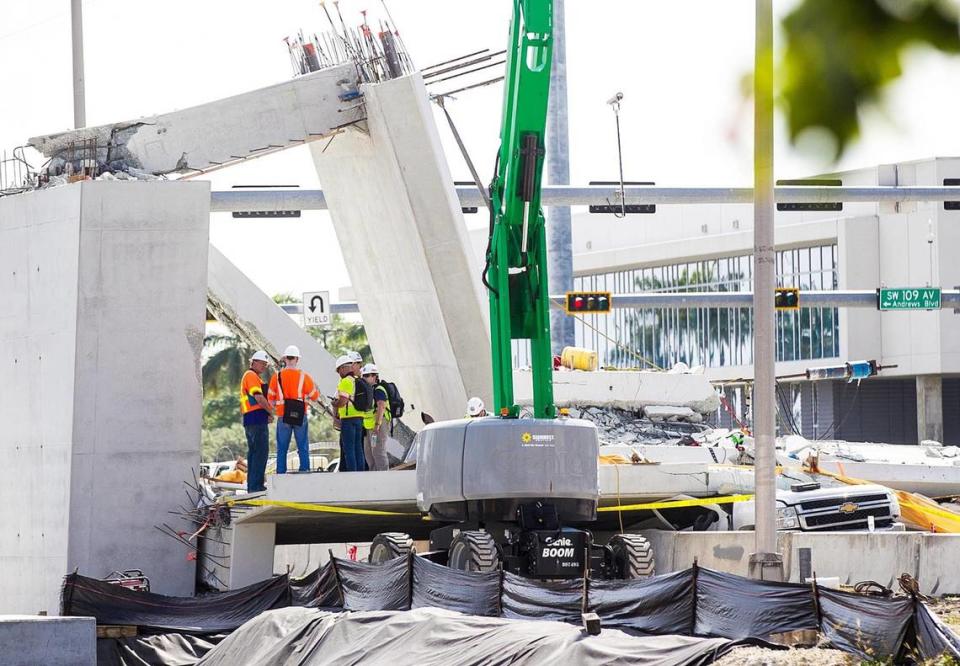 On Sunday, March 18, 2018, inspectors huddle around the northern end of the Florida International University Pedestrian Bridge, where cracks were found before the bridge collapsed. The section remains the focus of closer inspection. On the right, the last remaining vehicle is still under the rubble of concrete. The collapse on March 15 killed six people.