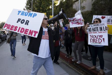 A Trump supporter walks past protesters outside the Luxe Hotel, where Republican presidential candidate Donald Trump was expected to speak in Brentwood, Los Angeles, California, United States July 10, 2015. REUTERS/Lucy Nicholson