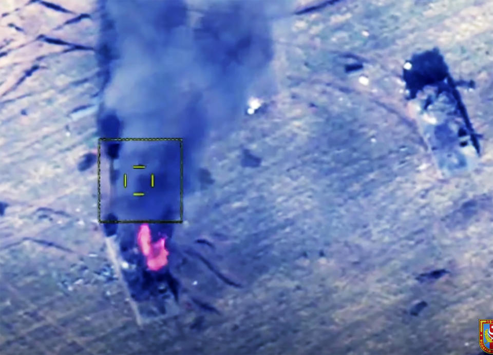 In this photo taken from a video released by Azerbaijan's Defense Ministry on Saturday, Oct. 10, 2020, Azerbaijan's forces attack the Armenian army's armored vehicles during a military conflict in the separatist region of Nagorno-Karabakh. With Russia's mediation, Armenia and Azerbaijan agreed to a cease-fire in Nagorno-Karabakh starting at noon Saturday following two weeks of heavy fighting that marked the worst outbreak of hostilities in the separatist region in a quarter-century. (Azerbaijan's Defense Ministry via AP)