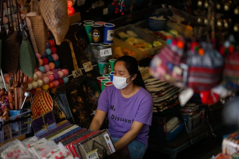 A woman wears a protective face mask due to the coronavirus disease (COVID-19) outbreak, as she waits for costumers in central Bangkok