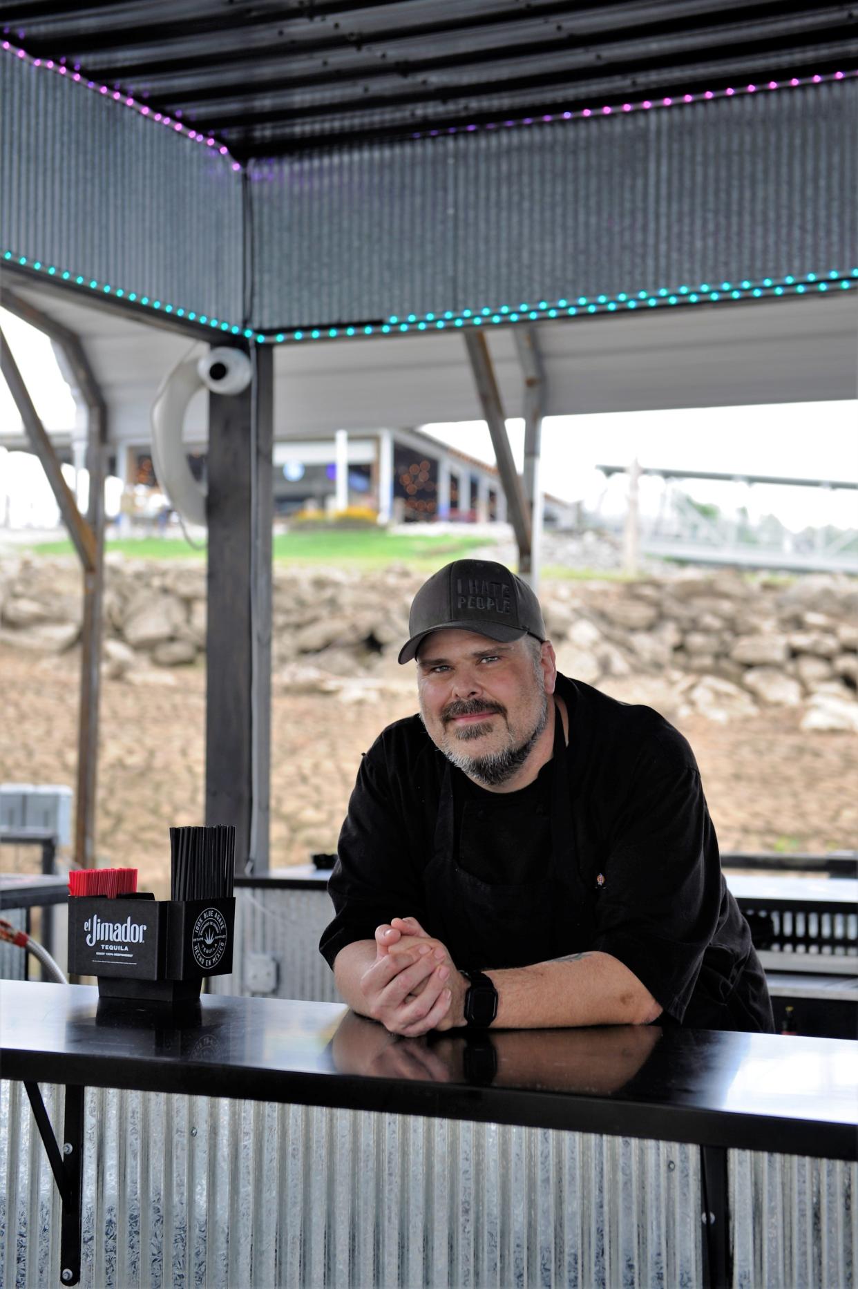Chef Nick Walls takes a breather on the Dive Barge on Thursday, Aug. 3, 2023. In the background is the Marina Point Bar, Grill and Nightclub.