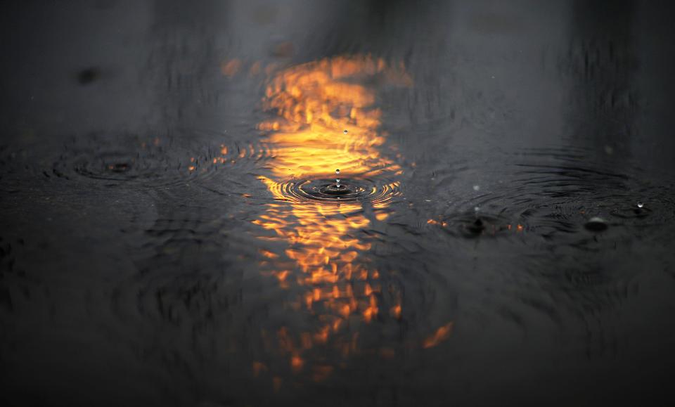 A rain drop falls in the reflection of the Olympic flame in a puddle at the 2014 Winter Olympics, Tuesday, Feb. 18, 2014, in Sochi, Russia. (AP Photo/David Goldman)