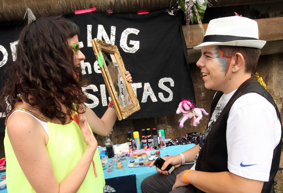 BERLIN, GERMANY - JULY 21: An attendee looks in the mirror after getting his face painted with glitter at the second annual Hipster Olympics on July 21, 2012 in Berlin, Germany. With events such as the "Horn-Rimmed Glasses Throw," "Skinny Jeans Tug-O-War," "Vinyl Record Spinning Contest" and "Cloth Tote Sack Race," the Hipster Olympics both mocks and celebrates the Hipster subculture, which some critics claim could never be accurately defined and others that it never existed in the first place. The imprecise nature of determining what makes one a member means that the symptomatic elements of adherants to the group vary in each country, but the archetype of the version in Berlin, one of the more popular locations for those following its lifestyle, along with London and Brooklyn, includes a penchant for canvas tote bags, the carbonated yerba mate drink Club Mate, analogue film cameras, an asymetrical haircut, 80s neon fashion, and, allegedly, a heavy dose of irony. To some in Berlin, members of the hipster "movement" have replaced a former unwanted identity in gentrifying neighborhoods, the Yuppie, for targets of criticism, as landlords raise rents in the areas to which they relocate, particularly the up-and-coming neighborhood of Neukoelln. (Photo by Adam Berry/Getty Images)