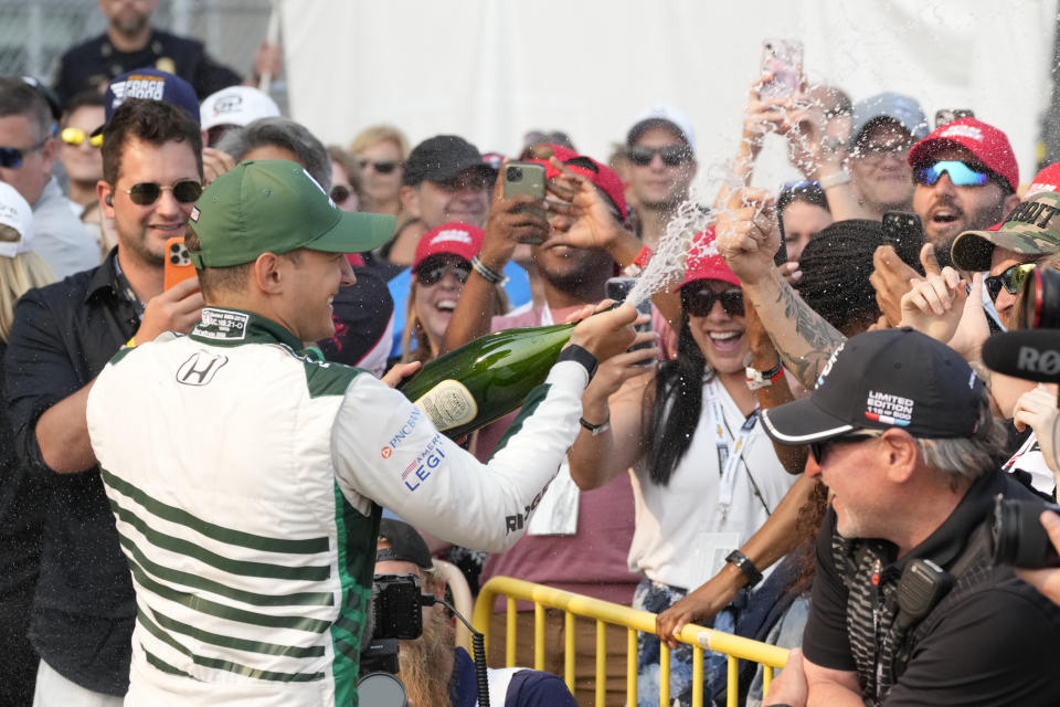 Alex Palou, front left, sprays fans after winning the IndyCar Detroit Grand Prix auto race, Sunday, June 4, 2023, in Detroit. (AP Photo/Carlos Osorio)