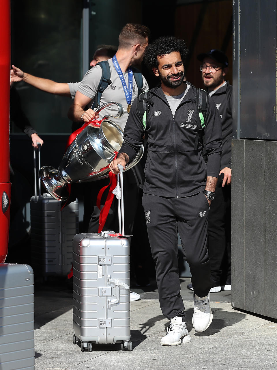 Liverpool's Mo Salah, followed by captain Jordan Henderson holding the Champions League trophy, leave the Eurostars Madrid Tower Hotel, as the team travel home for a homecoming parade.