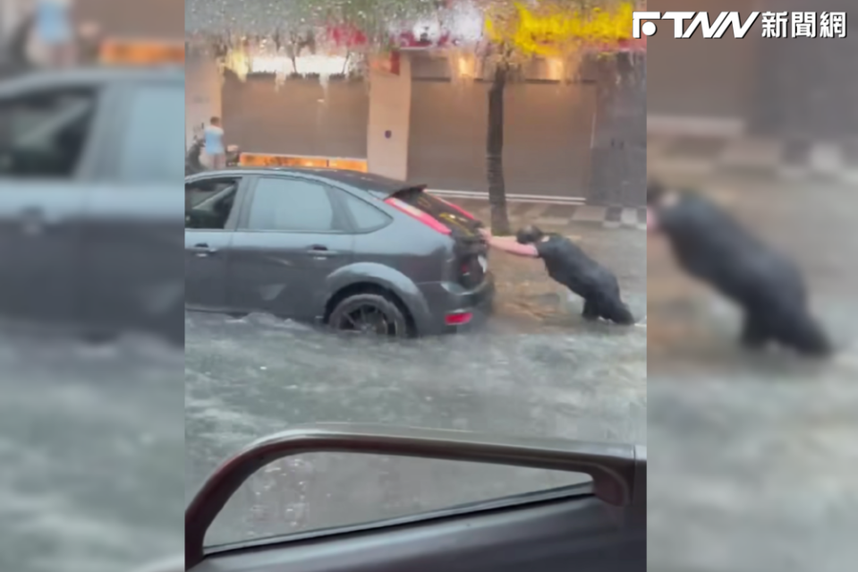 北市大同區重慶北路往國道嚴重積水，有汽車拋錨，駕駛在大雨中推車。（圖／記者爆料網）