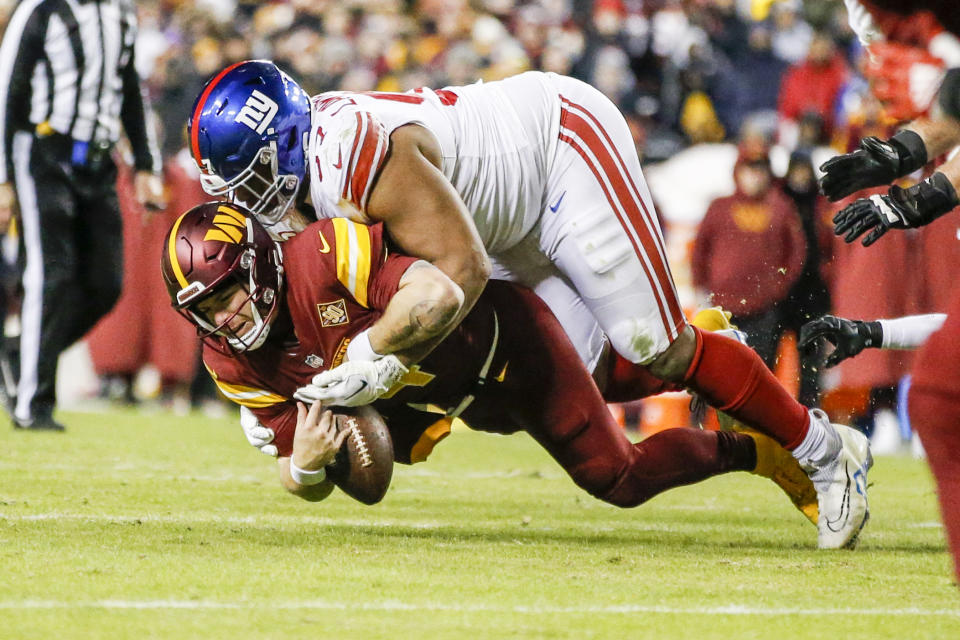 Washington Commanders quarterback Taylor Heinicke (4) fumbles the ball as New York Giants player Dexter Lawrence (97) tackles him during the second half of a NFL football game on Sunday, Dec. 18, 2022, in Landover, Md. (Shaban Athuman/Richmond Times-Dispatch via AP)