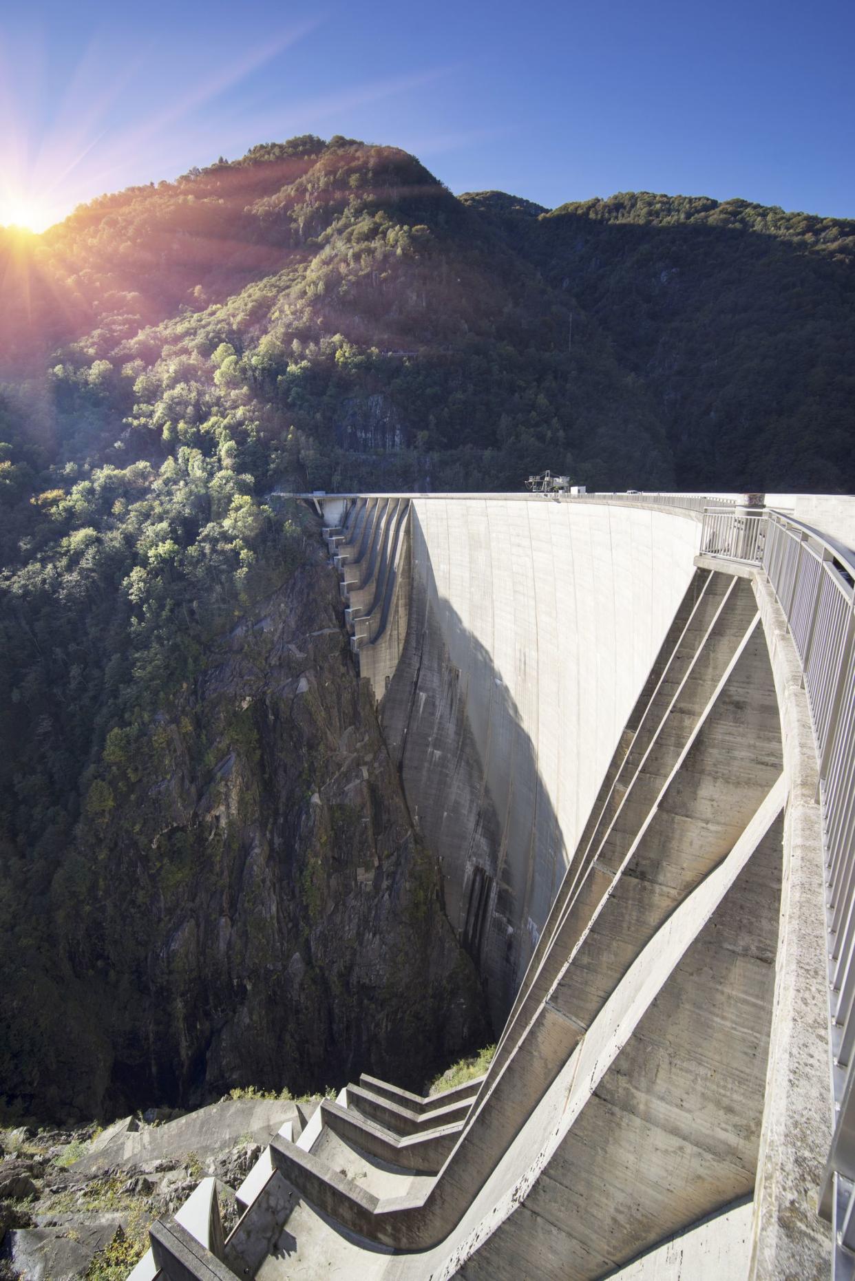 Contra Dam on the Verzasca River in the Val Verzasca of Ticino, Switzerland with the sun shining through the trees