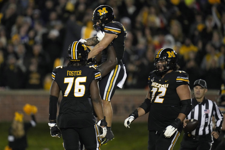 Missouri running back Cody Schrader, top, is congratulated by teammates after scoring during the first half of an NCAA college football game against Florida Saturday, Nov. 18, 2023, in Columbia, Mo. (AP Photo/Jeff Roberson)