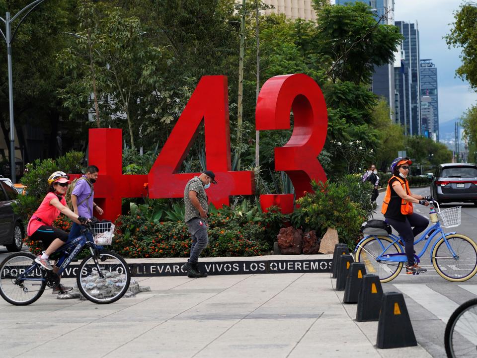 Bicyclists pedal past a monument dedicated to the 2014 disappearances of 43 students from a Guerrero state radical teacher college, in Mexico City on Aug. 20, 2022.