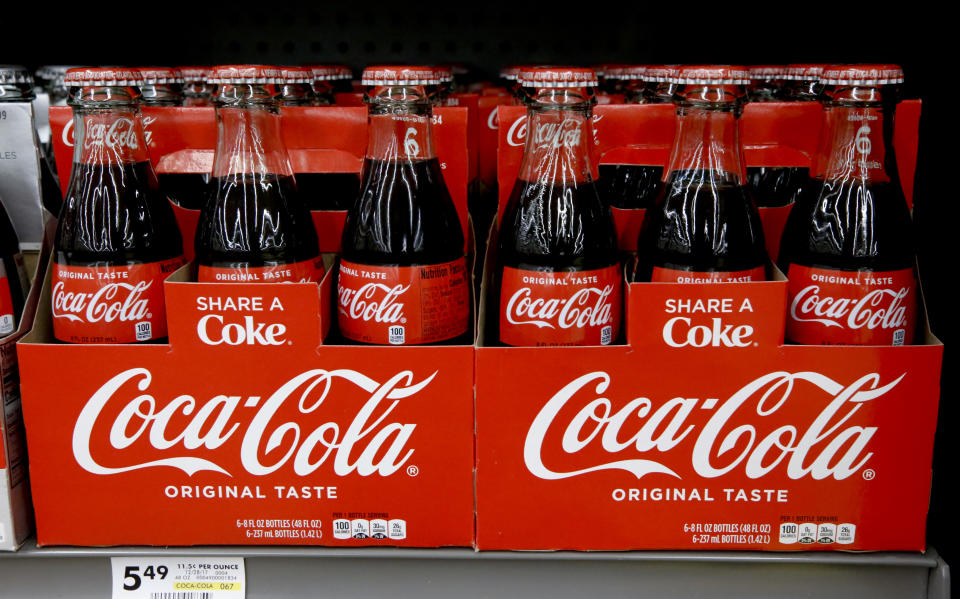 FILE--In this Aug. 8, 2018, file photo, bottles of Coca Cola sit on a shelf in a market in Pittsburgh. The Coca-Cola Company says that it's "closely watching" the growth of the use of a non-psychoactive element of cannabis in wellness drinks. (AP Photo/Gene J. Puskar, file)