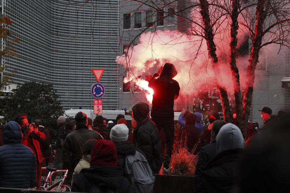 A protestors lights a flare during a demonstration against the reinforced measures of the Belgium government to counter the latest spike of the coronavirus in Brussels, Belgium, Sunday, Nov. 21, 2021. Many among them also protested against the strong advice to get vaccinated and any moves to impose mandatory shots. (AP Photo/Olivier Matthys)