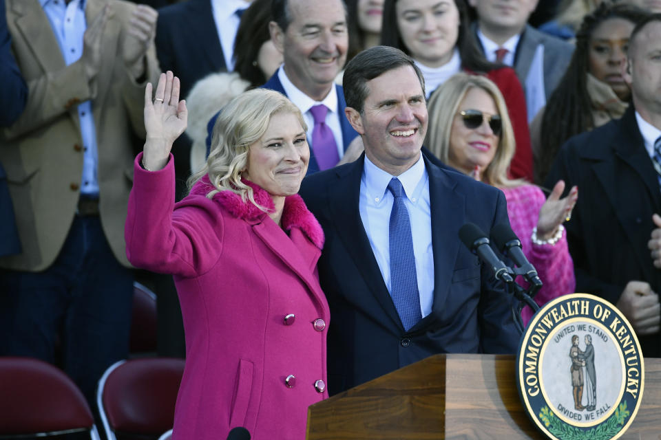 Kentucky Governor Andy Beshear, right, and his wife Britainy, wave to the crowd gathered to witness his public swearing in on the steps of the Kentucky State Capitol in Frankfort, Ky., Tuesday, Dec. 12, 2023. (AP Photo/Timothy D. Easley)