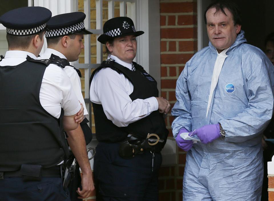 A forensics officer (R) leaves a house where the bodies of three children were found, in New Malden, southwest London April 23, 2014. A 43-year-old woman has been arrested on suspicion on murder after the bodies of three children were found at a house in southwest London, police said on Wednesday. Police said a four-year-old girl and two boys, both aged three, were found dead at a residential address in New Malden on Tuesday evening. REUTERS/Olivia Harris (BRITAIN - Tags: CRIME LAW SOCIETY)