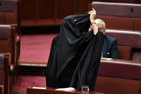 Australian One Nation party leader, Senator Pauline Hanson pulls off a burqa in the Senate chamber at Parliament House in Canberra, Australia, August 17, 2017. AAP/Mick Tsikas/via REUTERS