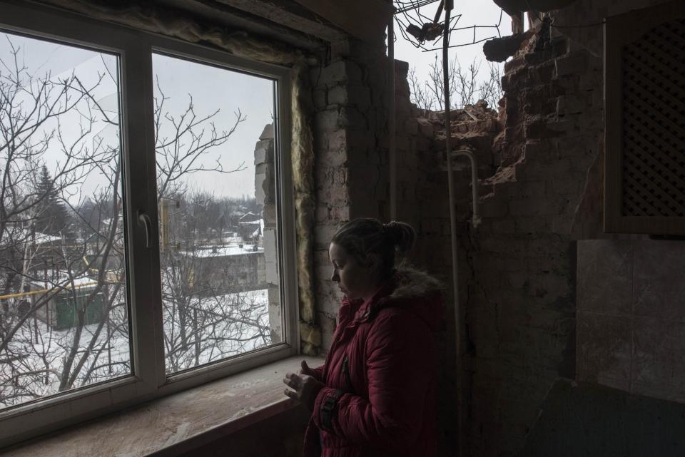 Olga Duzhikova looks through the window of her flat damaged by shelling in Avdiivka, Ukraine, Saturday, Feb. 4, 2017. Fighting in eastern Ukraine sharply escalated this week. Ukraine's military said several soldiers were killed over the past day in shelling in eastern Ukraine, where fighting has escalated over the past week. (AP Photo/Evgeniy Maloletka)