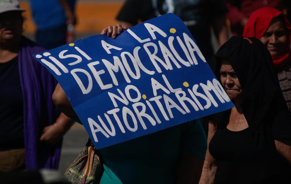 Protesters in El Salvador declare 'Yes to democracy. No to authoritarianism' during a demonstration on Jan. 14, 2024. <a href="https://www.gettyimages.com/detail/news-photo/women-walk-holding-up-a-sign-with-the-legend-yes-to-news-photo/1925903965?adppopup=true" rel="nofollow noopener" target="_blank" data-ylk="slk:PHOTOGRAFIA/Getty Images;elm:context_link;itc:0;sec:content-canvas" class="link ">PHOTOGRAFIA/Getty Images</a>