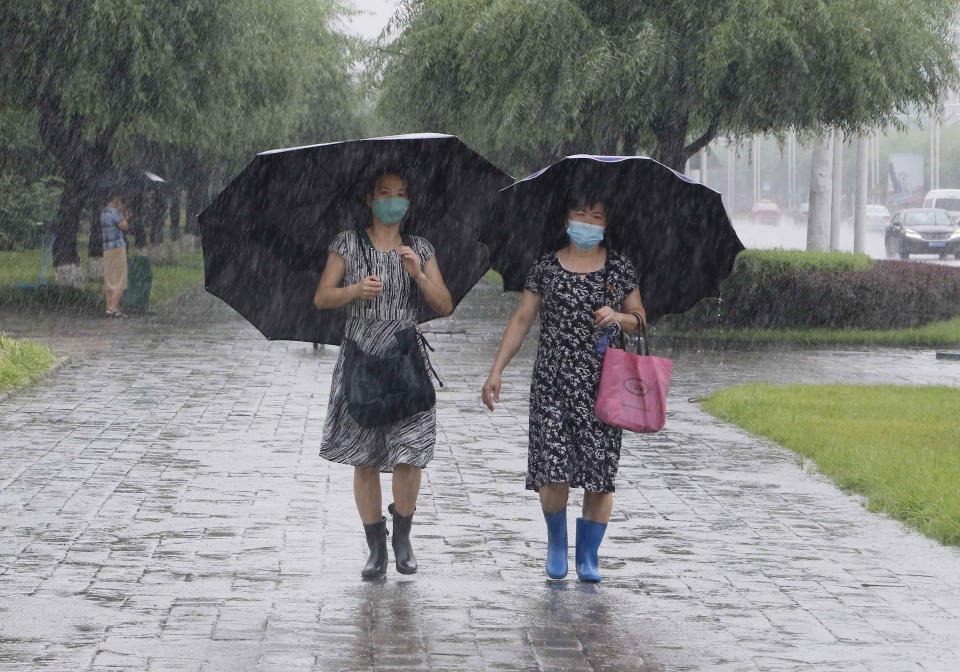 Women walk with umbrellas during torrential rains, Wednesday, August 5, 2020, in Pyongyang. North Korea says torrential rains have lashed the country, prompting outside worries about possible big damages in the impoverished country. (AP Photo/Cha Song Ho)