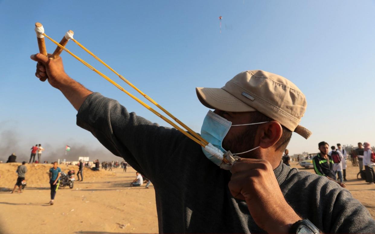 A Palestinian protester throws a rock with a slingshot in response to Israeli security forces' intervention during a protest - Anadolu