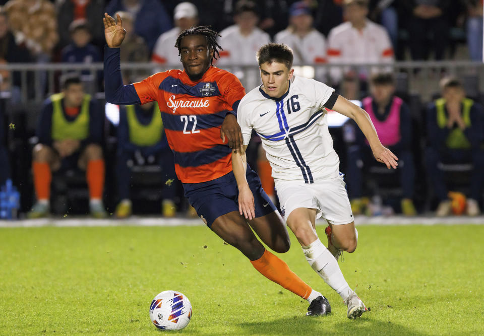 Syracuse's Olu Oyegunle (22) and Creighton's Jackson (16) chase the ball during the second half of an NCAA men's soccer tournament semifinal in Cary, N.C., Friday, Dec. 9, 2022. (AP Photo/Ben McKeown)